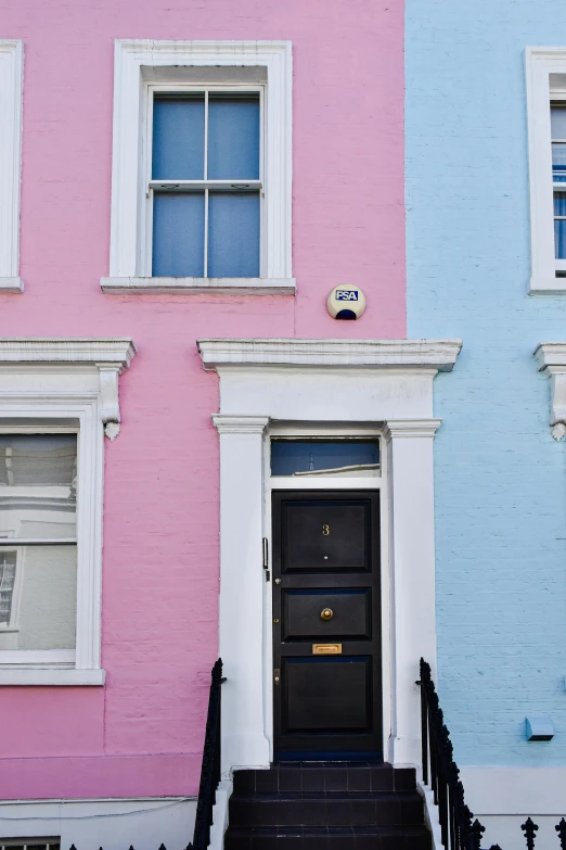 two buildings side by side with a black door and stairs