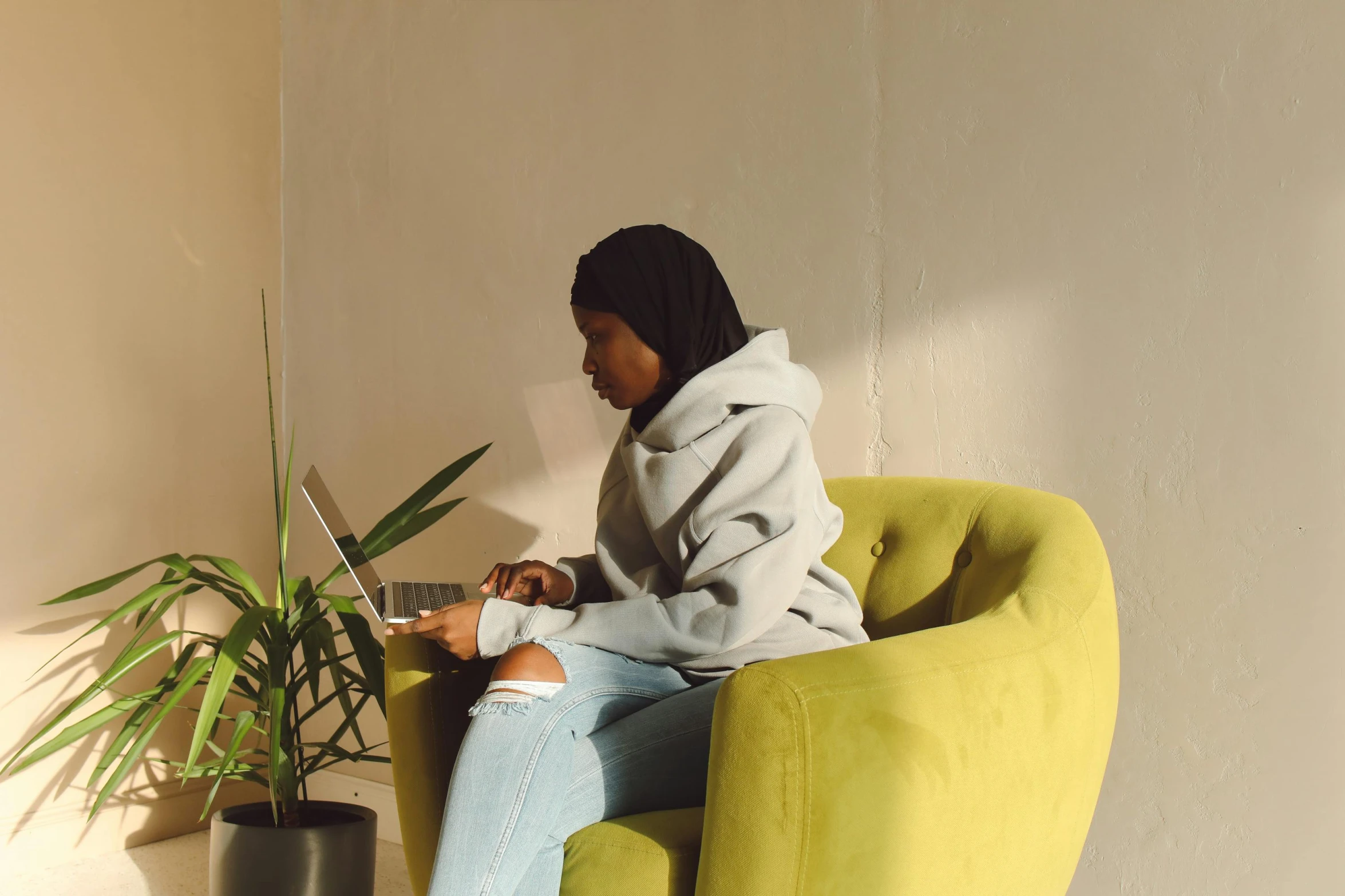 a person sitting on a chair with a laptop in her lap