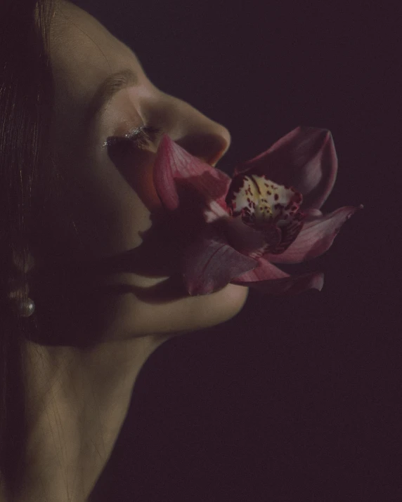 a girl's face holding a flower in her hand