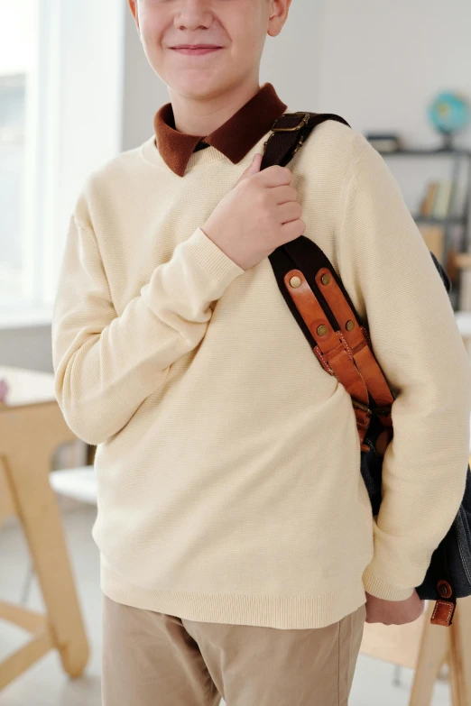 a little boy holding a bag that is wearing a brown cord