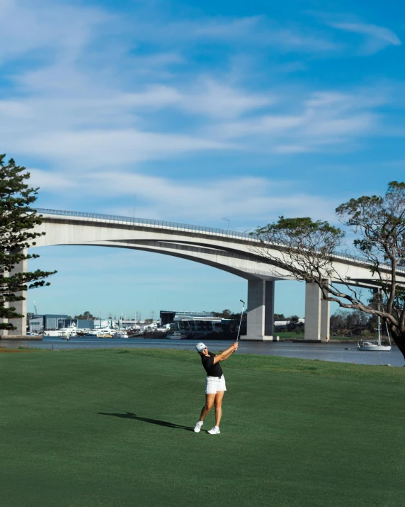 a woman holding her hand up in the air with a bridge above