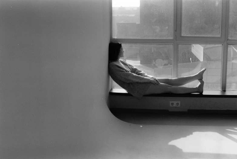 a woman sitting on a window sill looking out a window