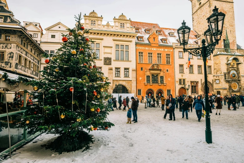 the tree is decorated with ornaments and people are walking around