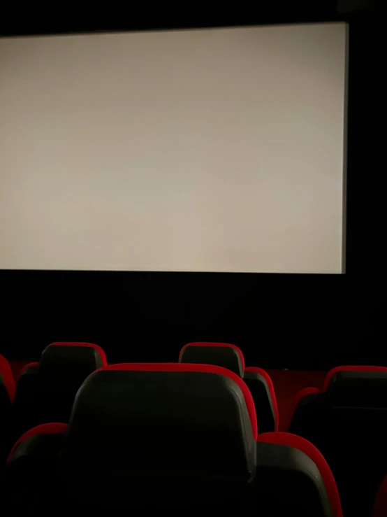 empty seats and projection screen in a dark theater