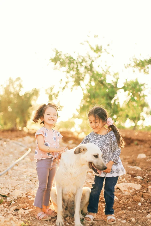 two young children playing with a dog in the dirt