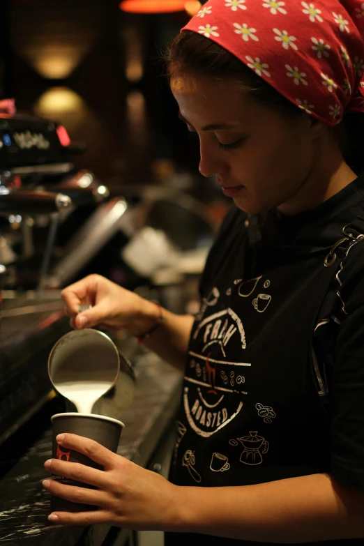 a woman pouring a drink into a cup at the bar