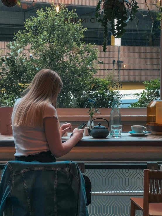 a woman is sitting at a table with plants