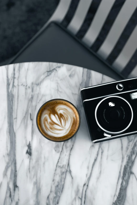 a coffee with a camera sits on a marble table