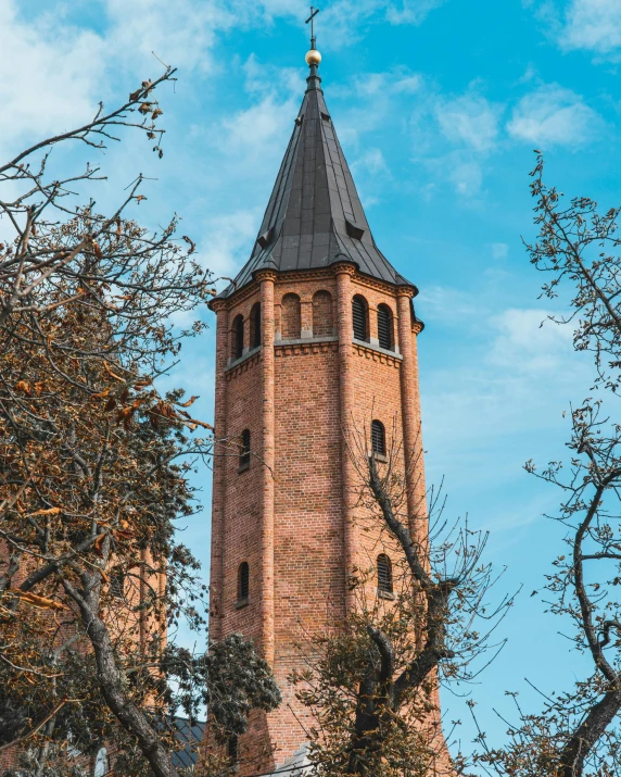 a tall brick clock tower surrounded by trees