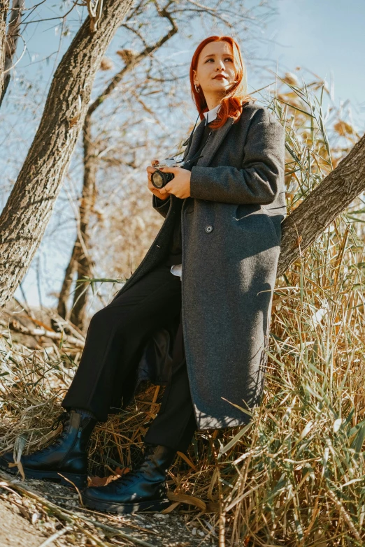 woman in an old coat sitting in a tree