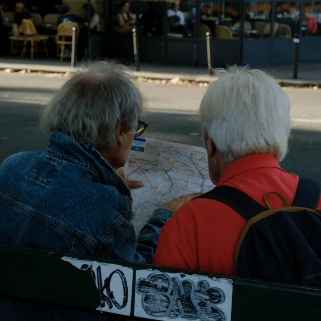 two people sitting on a bench at the city square