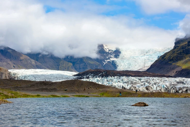 the people are standing in the water near the mountains