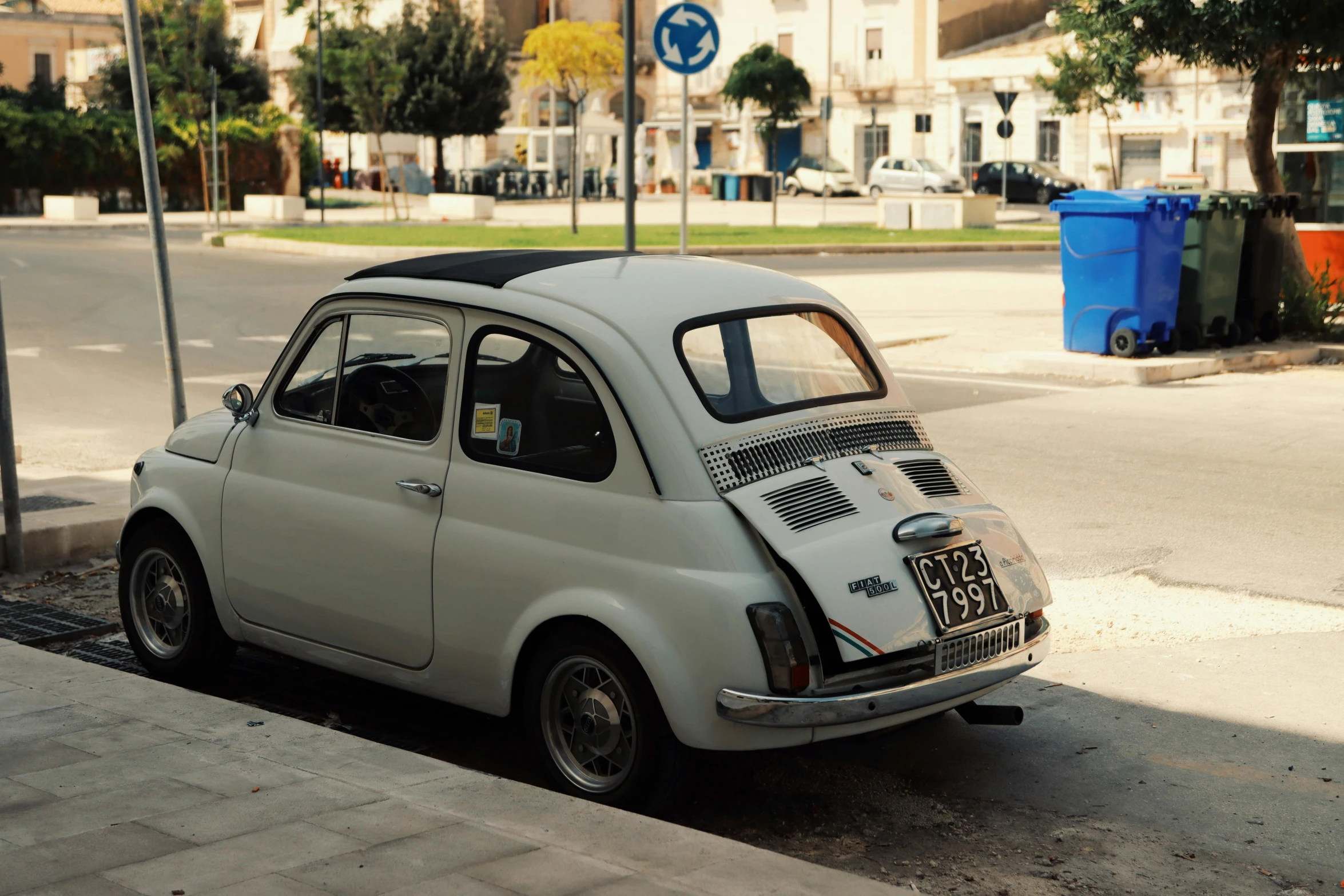 a small white car parked by the side of the road