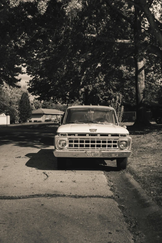 an old pick up truck parked on a road with lots of trees