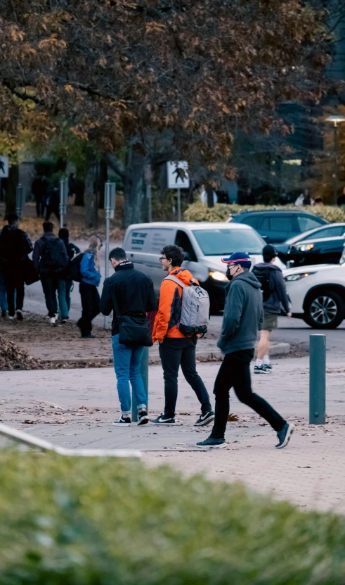 several people walking down a sidewalk near a street