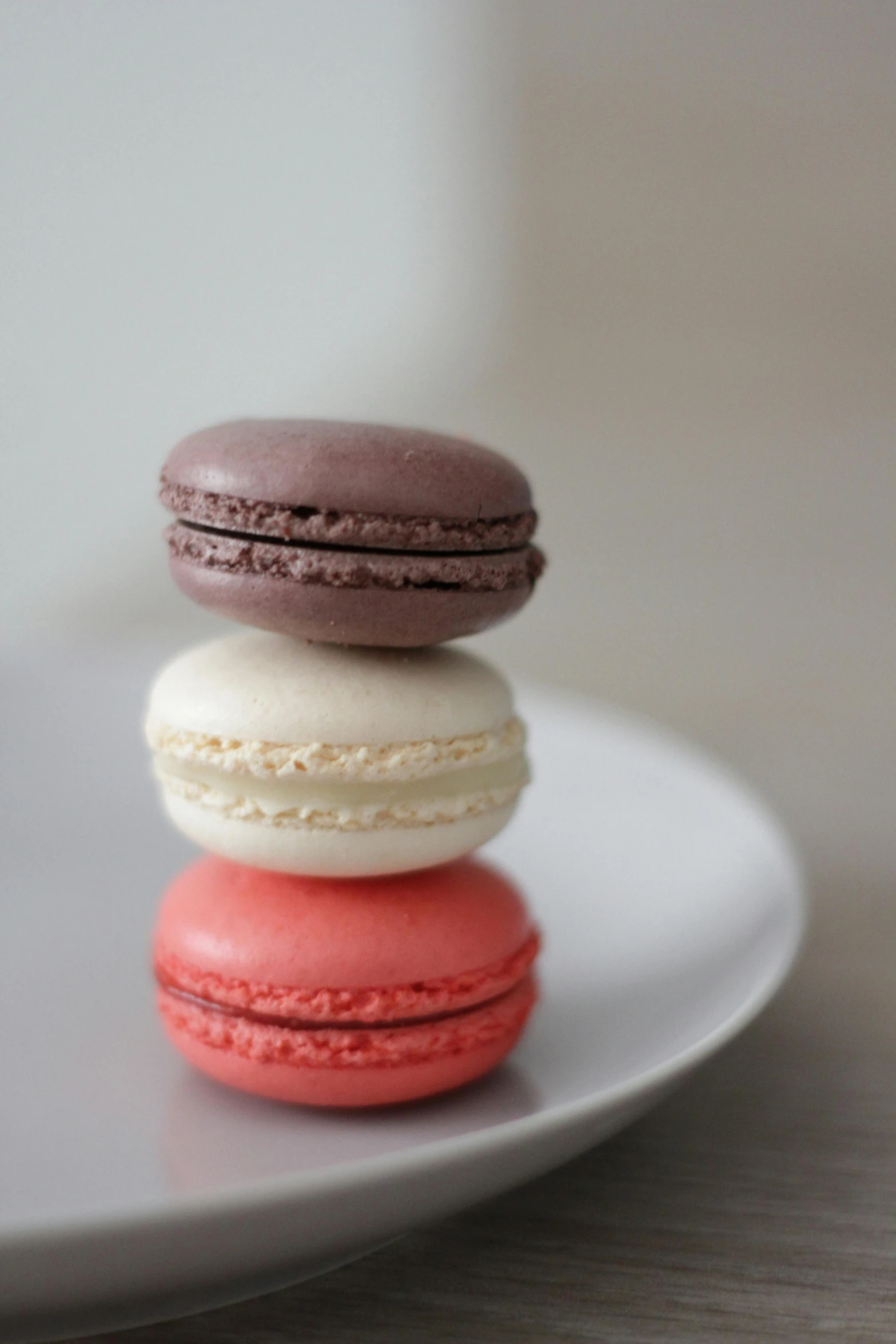 a small white plate holds three different colored macaroons