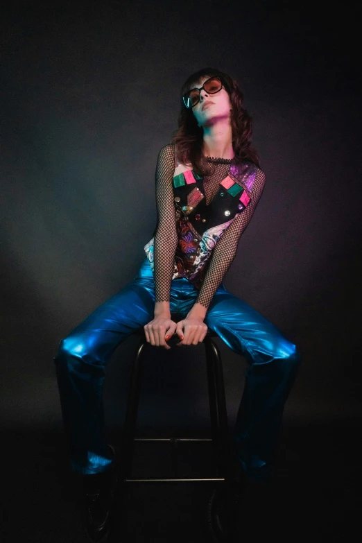 a woman sitting on top of a stool with her arms out