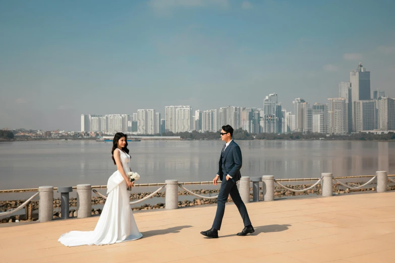 a man and woman walk together on the sidewalk near the water