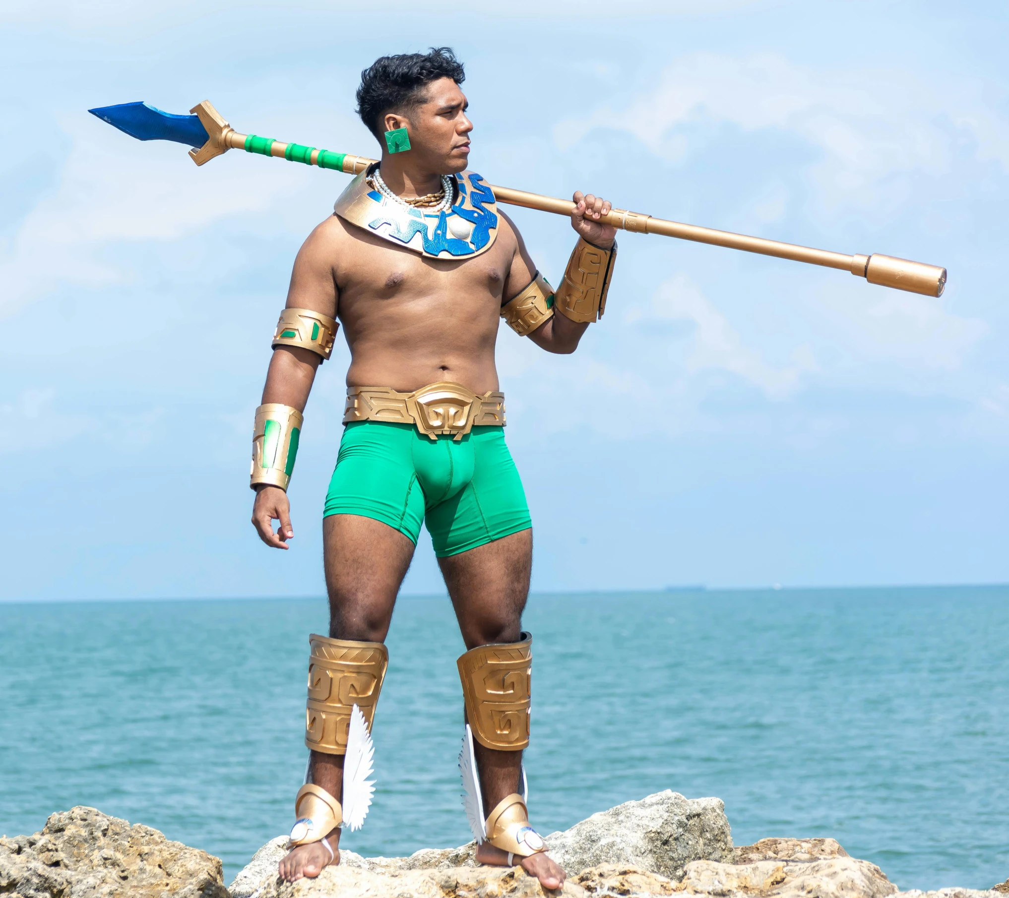 a man dressed as an egyptian warrior holding a spear and wearing green shorts