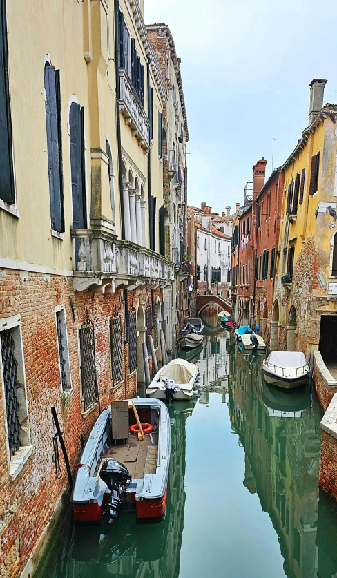 canal filled with docked boats next to tall buildings