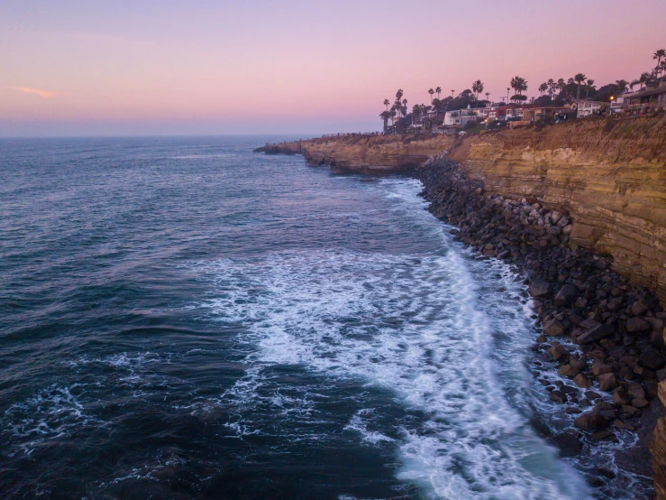 waves near the rocky coastline and houses at sunset