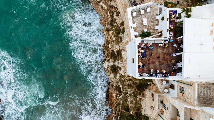 an aerial view shows the ocean and roof top terrace with tables