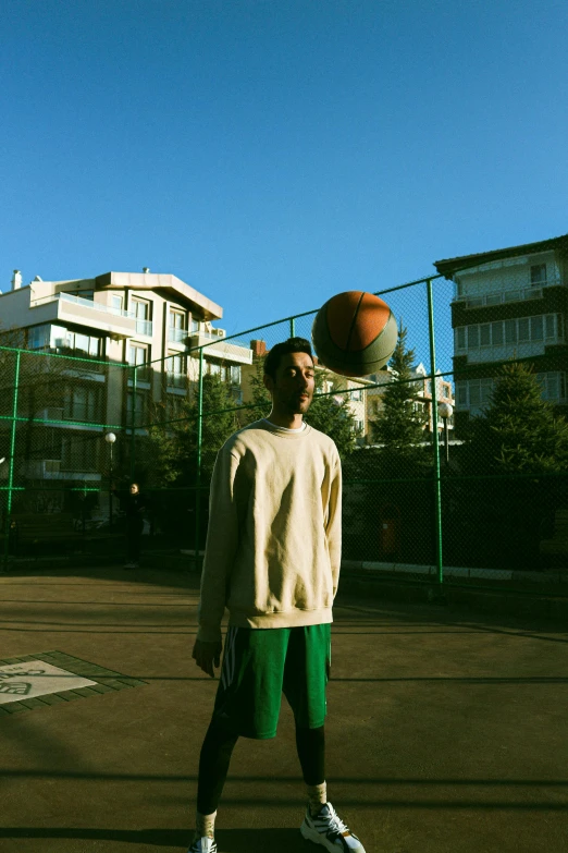 a man in a sweater stands in a basketball court