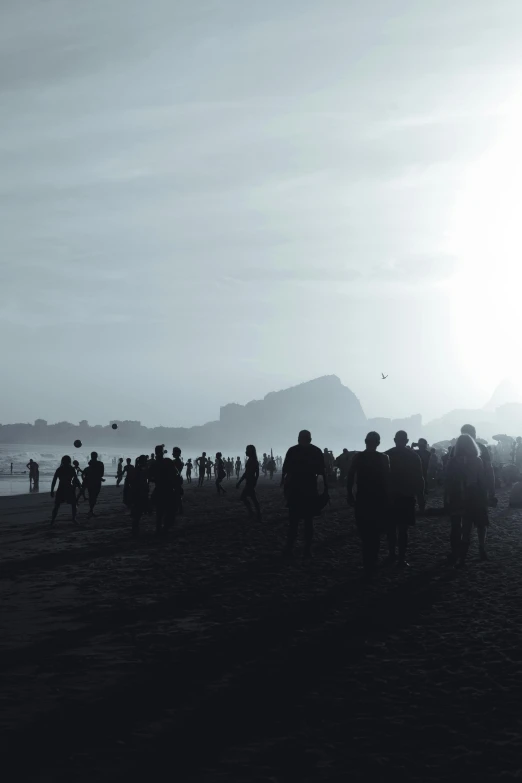 many people walking on the beach near the water