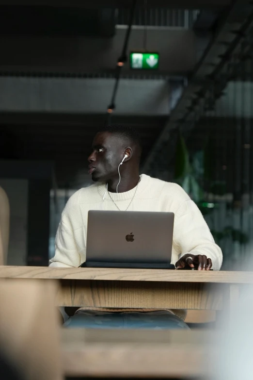 a man sitting at a wooden table using a laptop