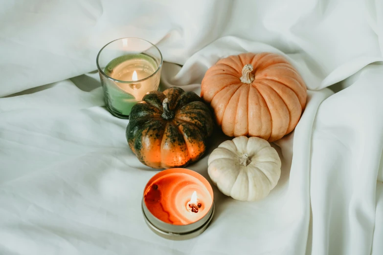 pumpkins and candles on a bed with sheets