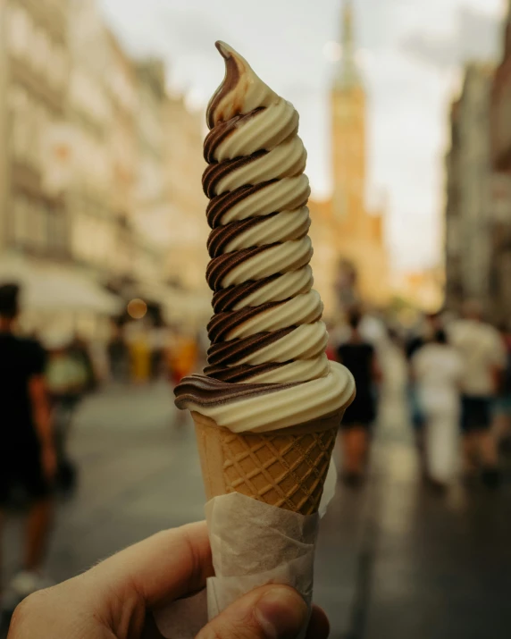 someone is holding a chocolate and cream ice - cream cone