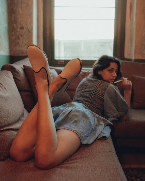 a woman lying on top of a brown couch