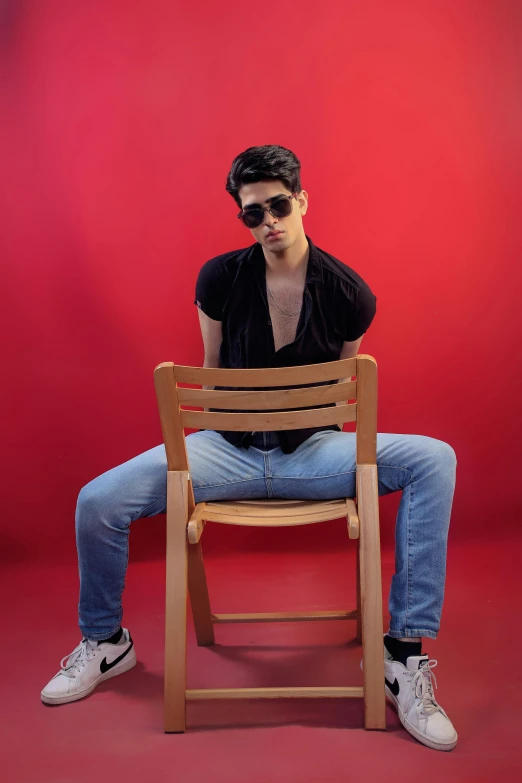 man sitting on chair with red background in studio