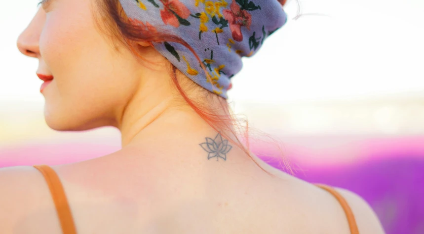 the back of a woman's head with a flower tattoo on her neck