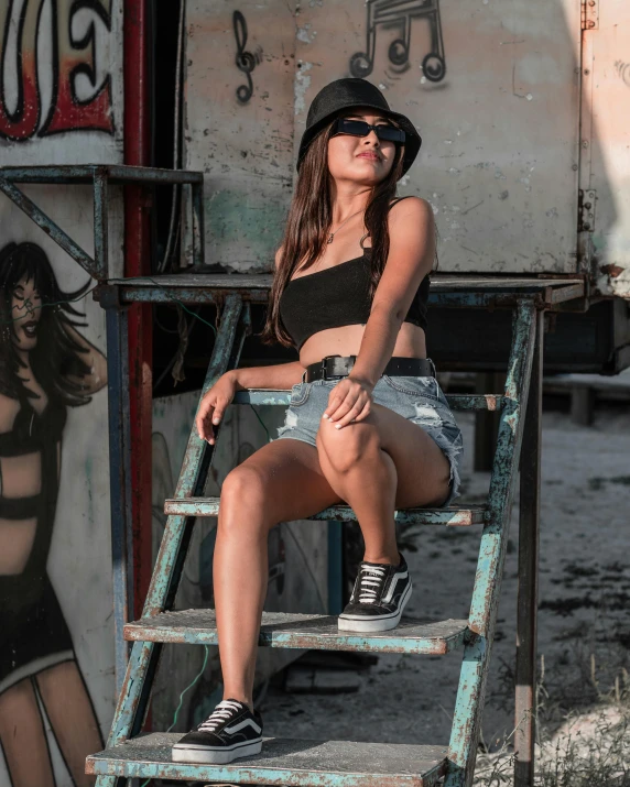 young woman in black top sitting on a chair near graffiti