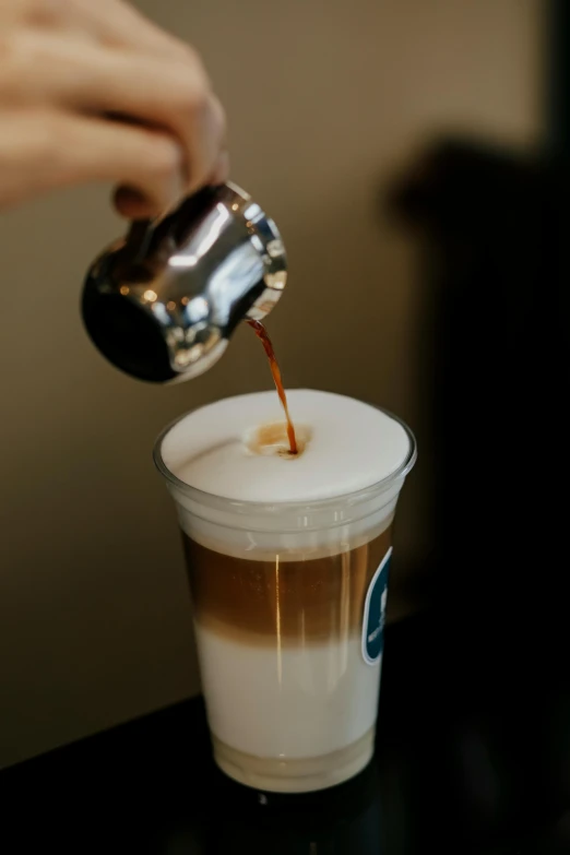 a person pours caramel into a glass full of coffee