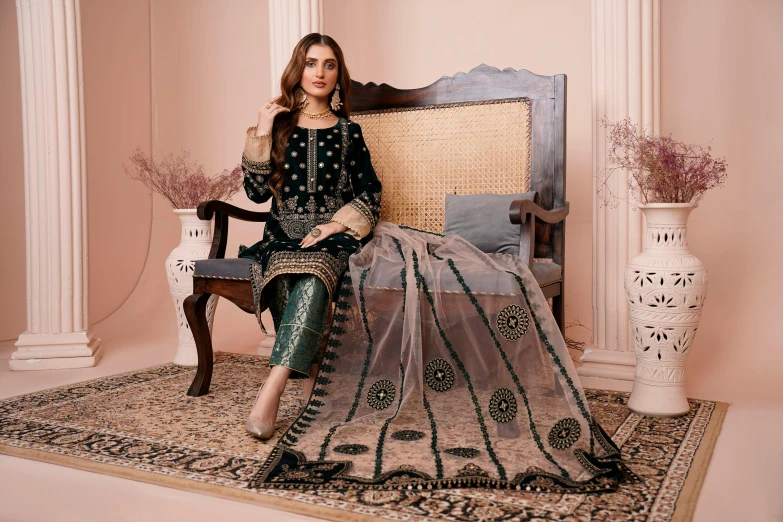 a women sitting on a chair with a green and beige sari covering over her