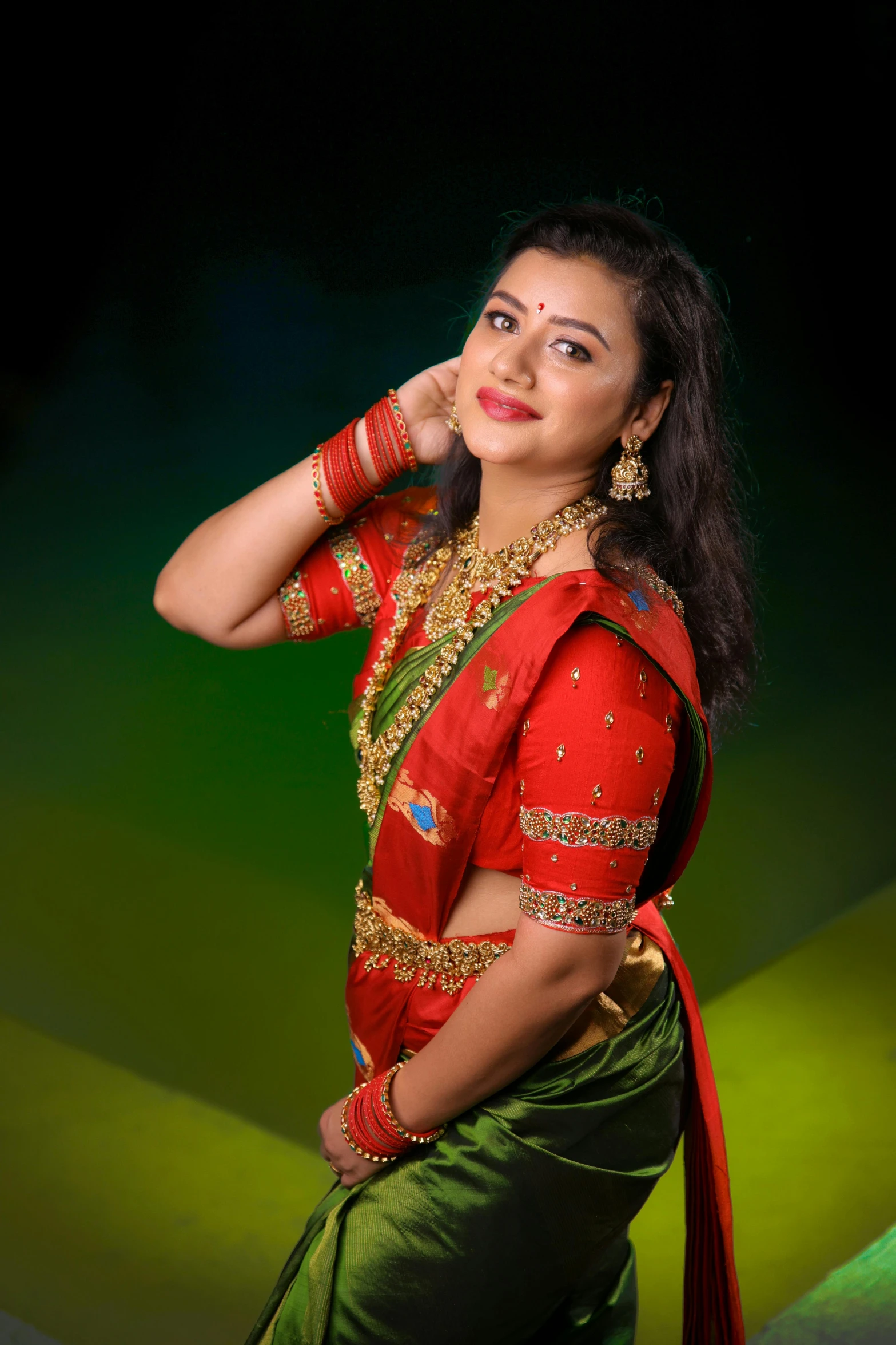 an indian woman in saree standing up against a green background