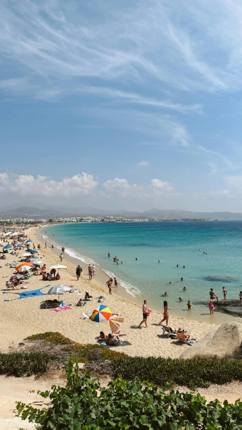 people on a beach near the ocean under clear blue skies