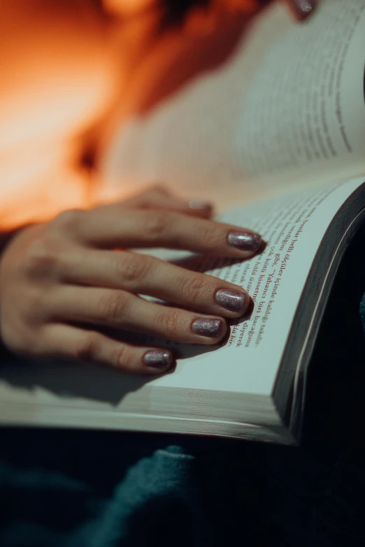 a woman reading a book with her nails on