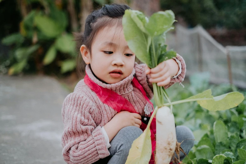 a girl holding up a plant in a garden