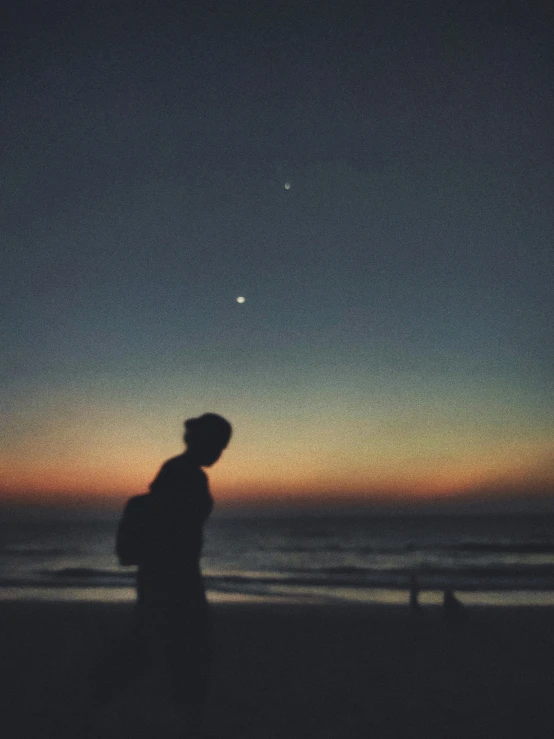 a silhouette of a man standing on a beach at sunset