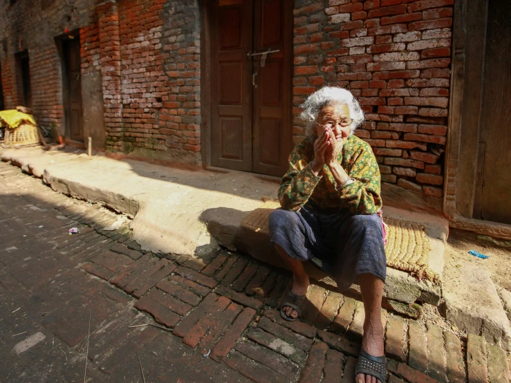 old lady sitting down on a city street