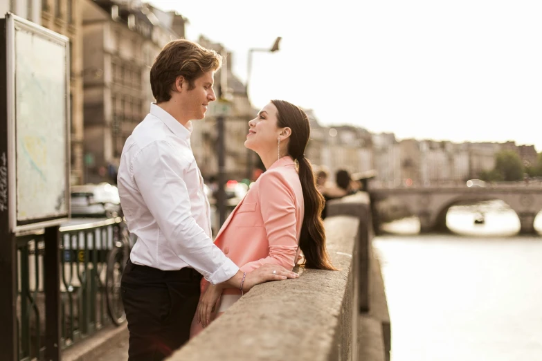 a couple standing by the water and looking into each others eyes