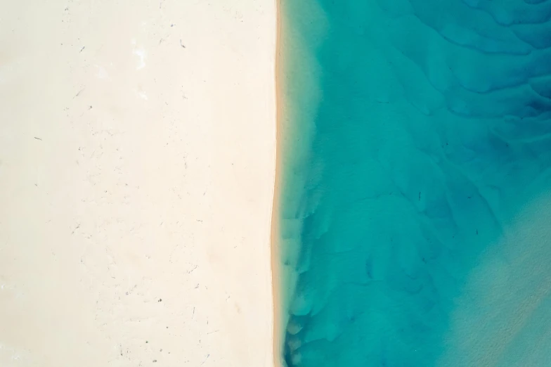 the water is blue and white next to a beach