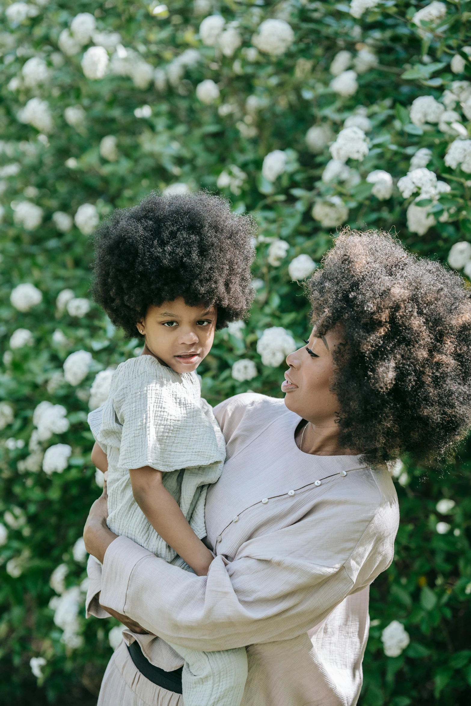 a woman holds a small child in front of a tree