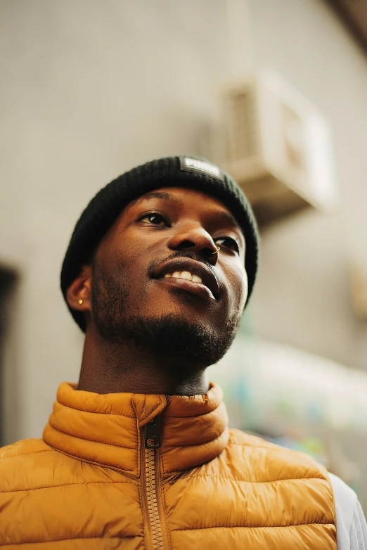 a man in a hat and puffy yellow vest is looking up