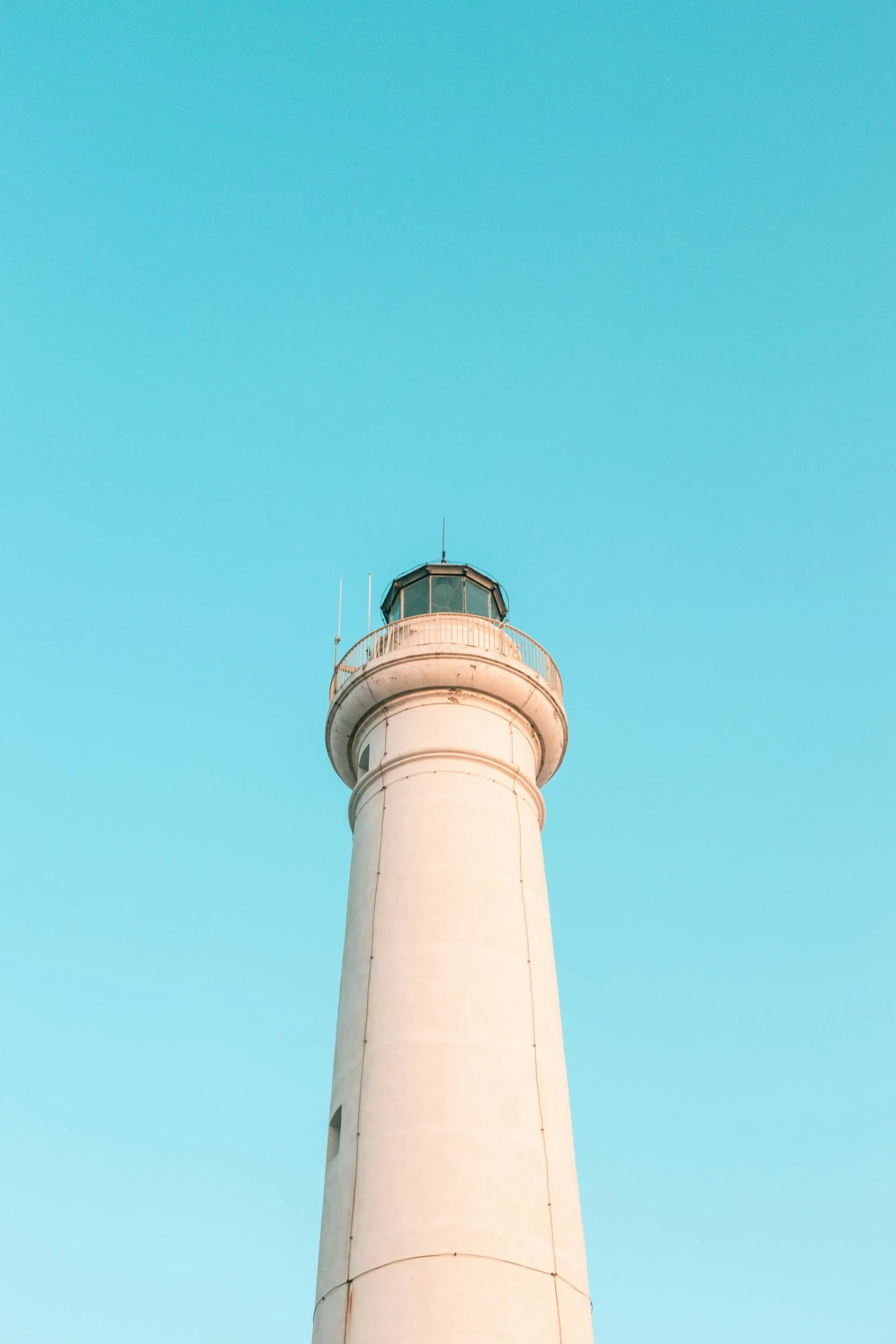 a white lighthouse sits against a blue sky