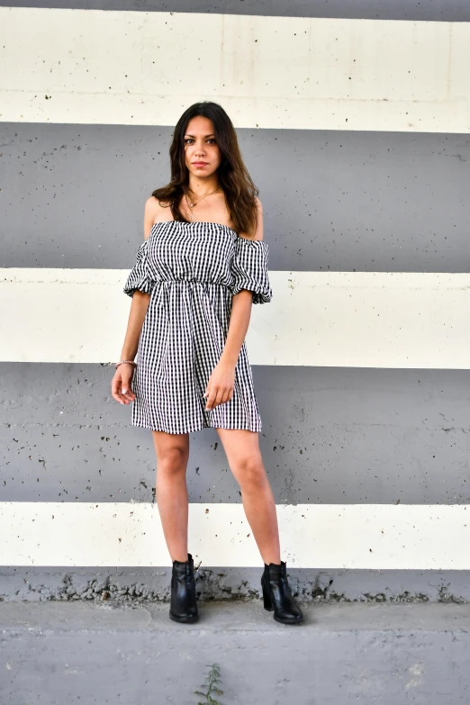 a girl posing in a black and white dress against a wall