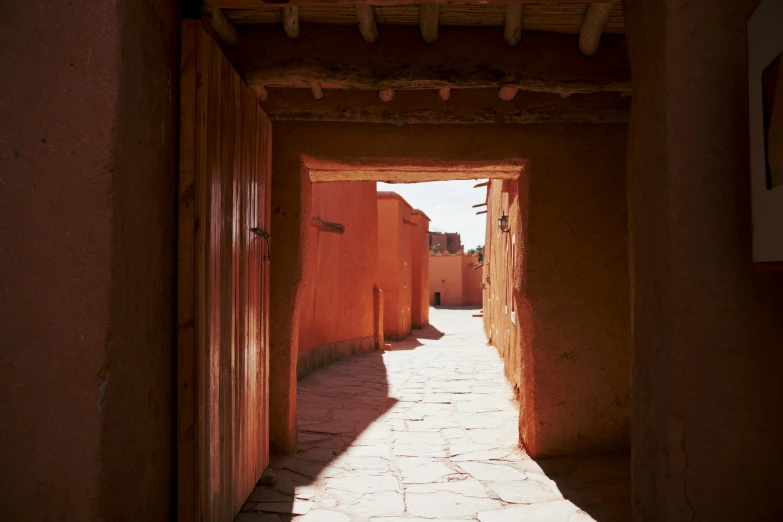 the sun shining through an arched doorway between adobe houses